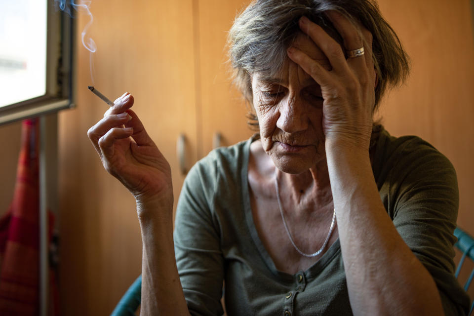 A woman is sitting in a very depressed mood, holding cigarette