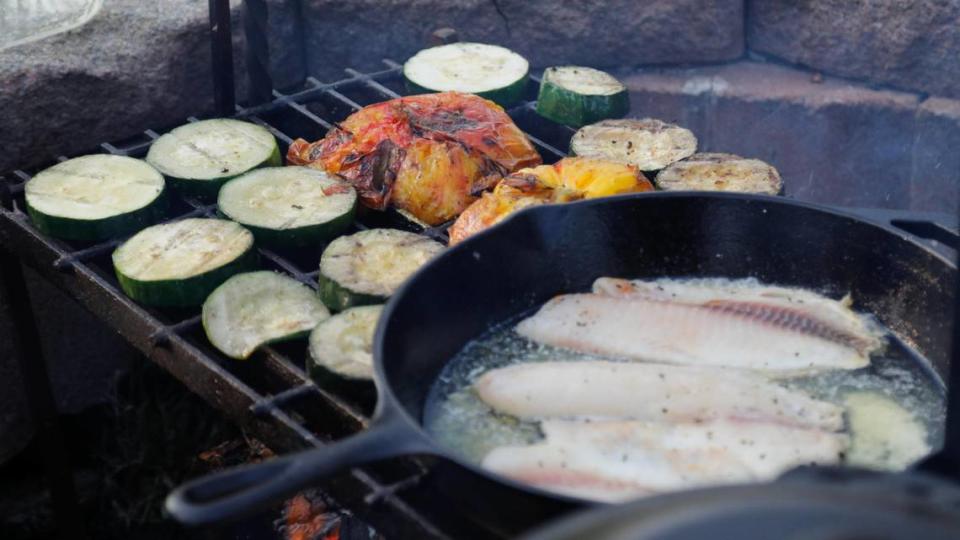 Cucumbers, tomatoes and tilapia cooks over a campfire on Tuesday, July 25, 2023 at Bourbon Barrel Cottages in Lawrenceburg, Ky.