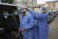Municipal workers remove their protective gear after collecting presidential election ballots from an elderly care home in Montijo, south of Lisbon, Tuesday, Jan. 19, 2021. For 48 hours from Tuesday, local council crews are collecting the votes from people in home quarantine and from residents of elderly care homes ahead of Sunday's presidential election. (AP Photo/Armando Franca)