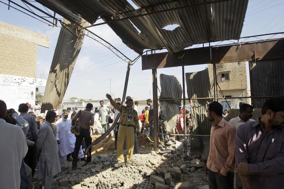 Pakistanis gather at the site of a bomb blast, in Karachi, Pakistan, Monday, Nov. 26, 2012. A bomb hidden in a cement construction block exploded in the southern city of Karachi killing at least one person and injuring several others, a police official said. (AP Photo/Shakil Adil)