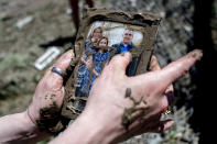 Sanford resident Kendra Tucker wipes away muck after finding a family photo for her aunt and uncle after their home was washed away in flood waters, Thursday, May 21, 2020, in Sanford, Mich. Scores of displaced people are staying in shelters after flooding overwhelmed two dams, submerged homes and washed out roads in Central Michigan. (Jake May/MLive.com/The Flint Journal via AP)