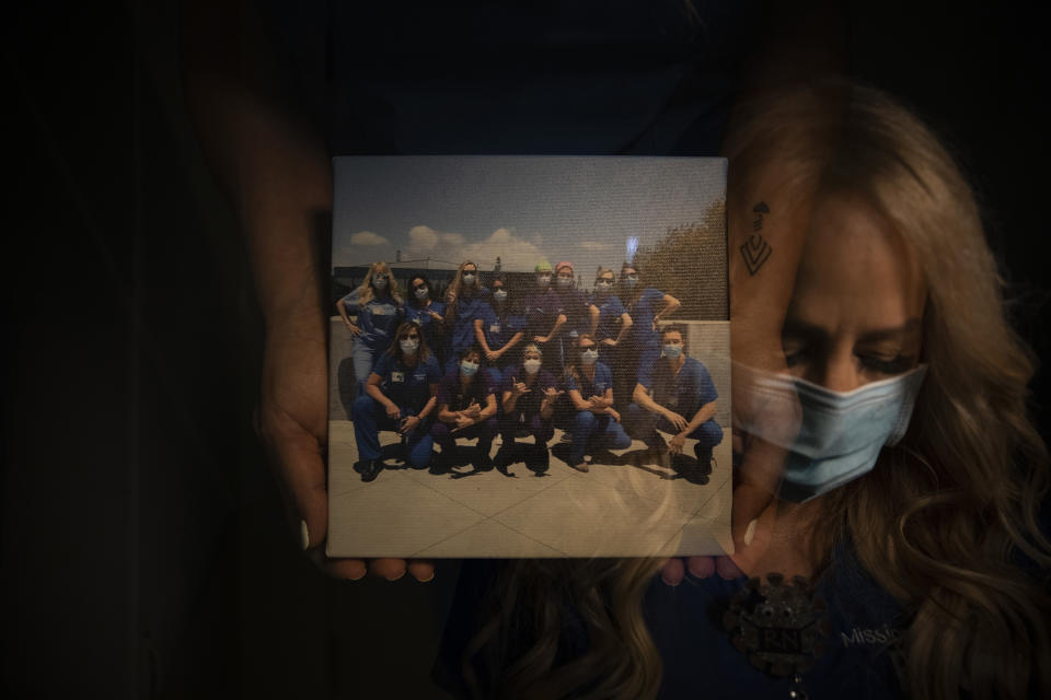 In this photo created with an in-camera multiple exposure, registered nurse Debbie Wooters, part of a group of nurses who had been treating coronavirus patients in an intensive care unit, holds a group picture taken with her fellow nurses in the empty COVID-19 ICU at Providence Mission Hospital in Mission Viejo, Calif., Tuesday, April 6, 2021. Many patients were frightened when told they would be put on a ventilator. Wooters remembers a patient who "looked at me and said, through his gasping breath, 'I don't want to die.'" (AP Photo/Jae C. Hong)