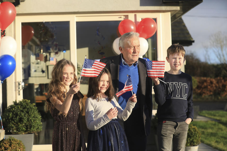 Joe Biden's cousins Brendan Blewitt with his grandchildren Emily, Lauren, and Darragh wave their U.S. flags to the media from their home in Knockmore, near the town of Ballina in Ireland, Wednesday, Jan. 20, 2021. Biden has officially become the 46th president of the United States. His great-great grandfather Patrick Blewitt was born in, County Mayo, in 1832. He left for the US in 1850, aged 18. (AP Photo/Peter Morrison)