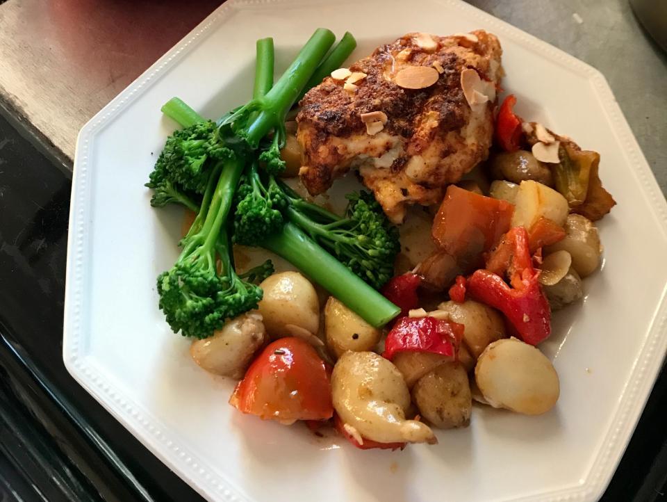 A plate of Romesco chicken traybake with potatoes, peppers, and broccoli.