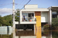 Residents stand on their balcony over a flooded street after heavy rain in Canoas, Rio Grande do Sul state, Brazil, Thursday, May 9, 2024. (AP Photo/Carlos Macedo)