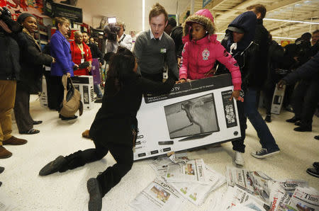 Shoppers wrestle over a television as they compete to purchase retail items on "Black Friday" at an Asda superstore in Wembley, north London November 28, 2014. REUTERS/Luke MacGregor