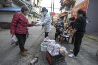 In this March 18, 2020 photo, people buy pork at the entrance gate of a closed residential community in Wuhan in central China's Hubei Province. Last month, Wuhan was overwhelmed with thousands of new cases of coronavirus each day. But in a dramatic development that underscores just how much the outbreak has pivoted toward Europe and the United States, Chinese authorities said Thursday that the city and its surrounding province had no new cases to report. The virus causes only mild or moderate symptoms, such as fever and cough, for most people, but severe illness is more likely in the elderly and people with existing health problems. (Chinatopix via AP)