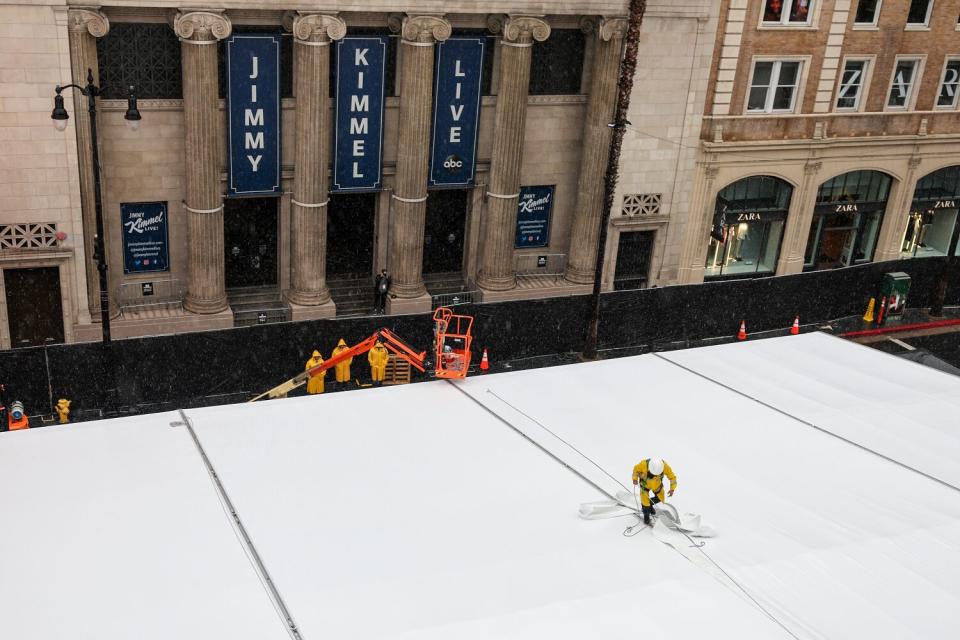 Workers rush to cover a leaky roof as rain falls outside as prep for the 95th Academy Awards on Hollywood Blvd. continues.