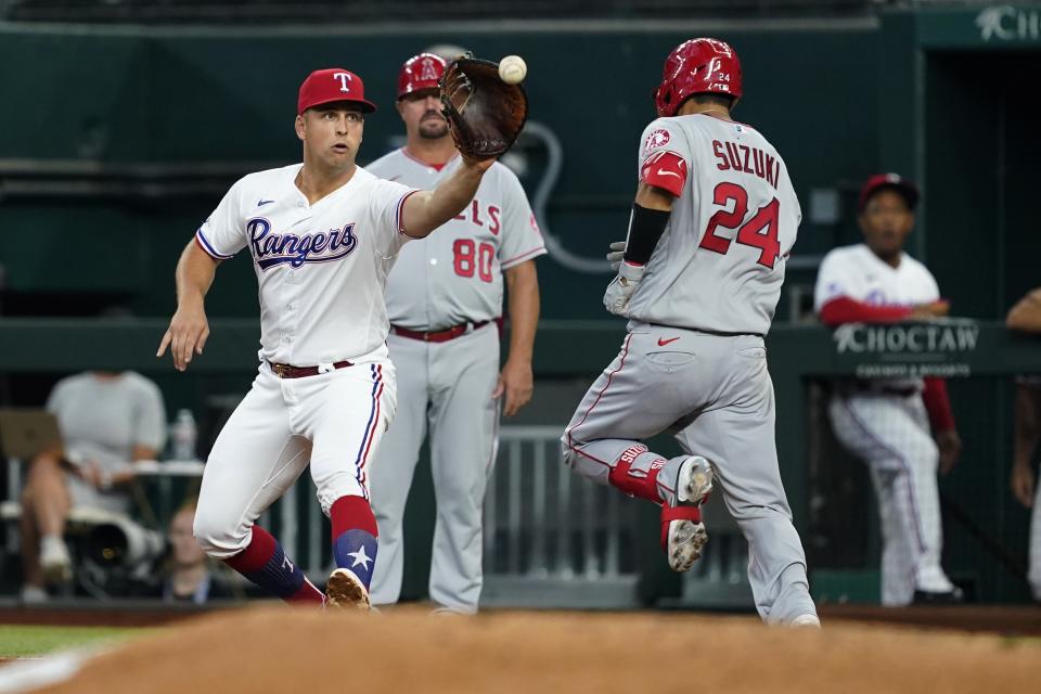 Texas Rangers first baseman Nathaniel Lowe, left, reaches out for the throw to get the out on a sacrifice bunt by Los Angeles Angels' Kurt Suzuki (24) in the fourth inning of a baseball game in Arlington, Texas, Thursday, Sept. 22, 2022. Jo Adell advanced to second on the play. (AP Photo/Tony Gutierrez)