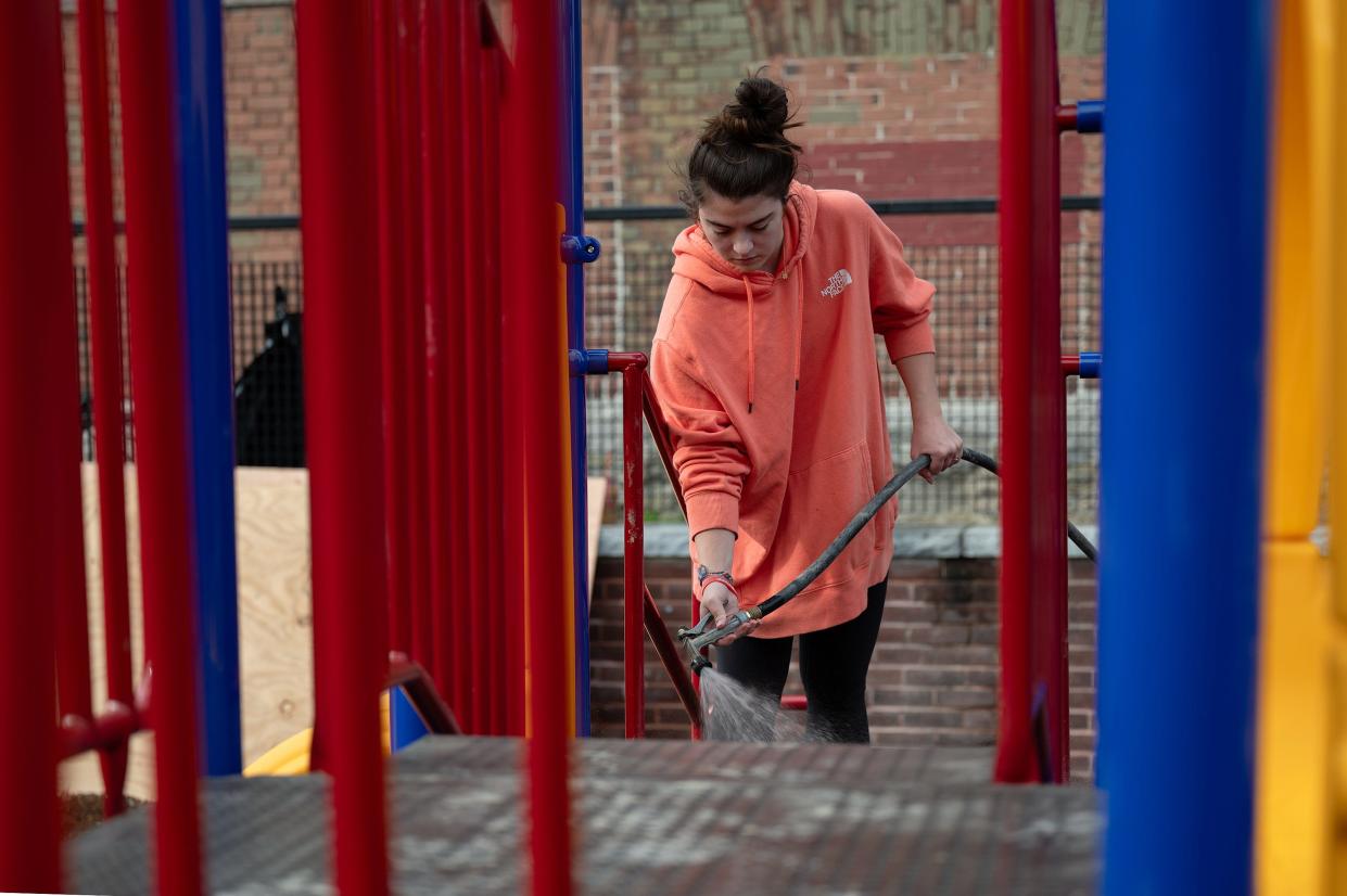 Marley Rehm, a Holy Cross junior, cleans the new playground volunteers built at Union Hill Elementary School on Saturday.