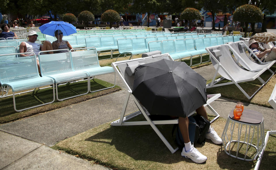 Spectators protect themselves from the heat with umbrellas as they watch tennis on a large video screen at the Australian Open tennis championships in Melbourne on Friday. (Photo: Aaron Favila/ASSOCIATED PRESS)