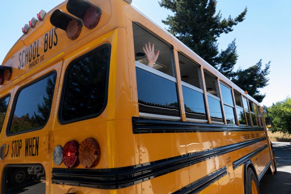 A student waves from a school bus.