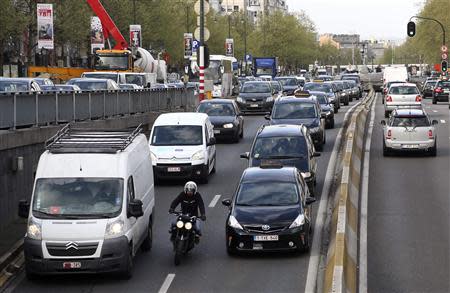 A motorcyclist rides his bike between cars during the morning rush hour in central Brussels April 8, 2014. REUTERS/Francois Lenoir