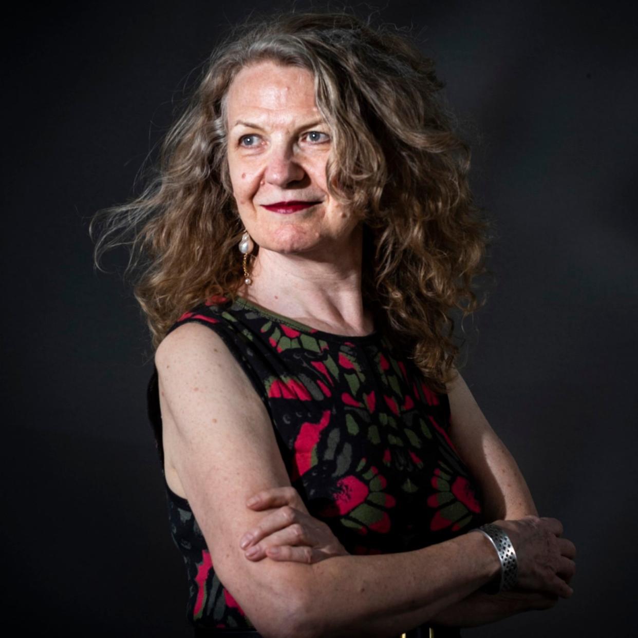 Joan Smith poses for a portrait against a black background with her her loose