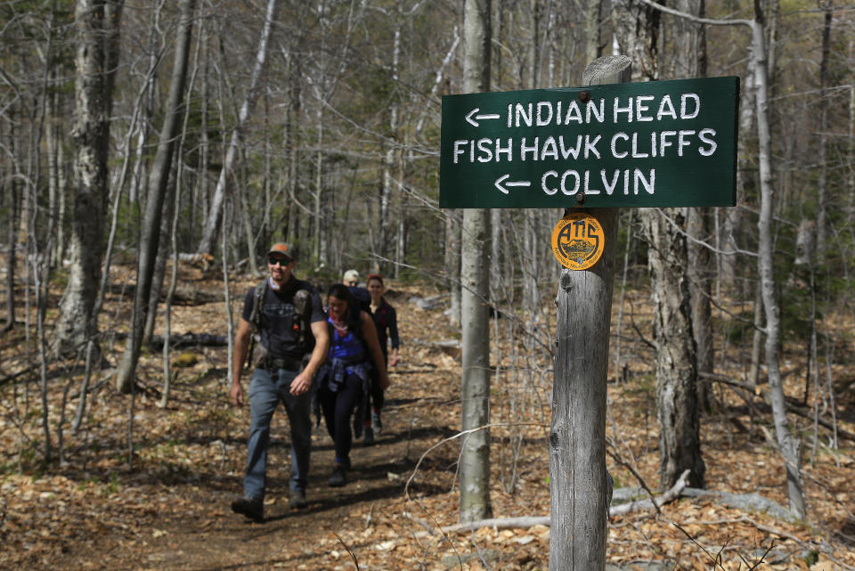 Hikers walk along the trail from Indian Head summit inside the Adirondack Mountain Reserve, Saturday, May 15, 2021, near St. Huberts, N.Y. A free reservation system went online recently to control the growing number of visitors packing the parking lot and tramping on the trails through the private land of the Adirondack Mountain Reserve. The increasingly common requirements, in effect from Maui to Maine, offer a trade-off to visitors, sacrificing spontaneity and ease of access for benefits like guaranteed parking spots and more elbow room in the woods. (AP Photo/Julie Jacobson)