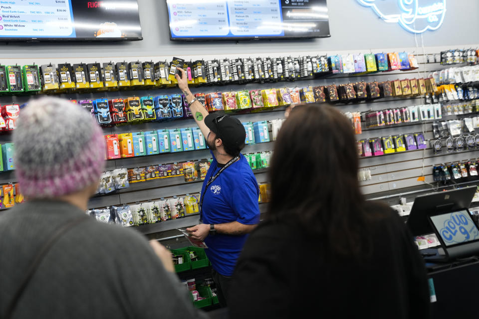 Cloud 9 Cannabis employee Kyler Hollingsworth grabs a product for customers, Saturday, April 13, 2024, in Arlington, Wash. The shop is one of the first dispensaries to open under the Washington Liquor and Cannabis Board's social equity program, established in efforts to remedy some of the disproportionate effects marijuana prohibition had on communities of color. (AP Photo/Lindsey Wasson)