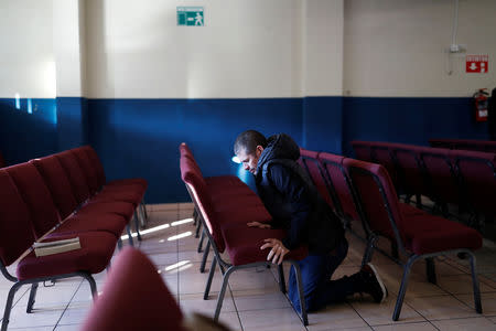 Honduran migrant Alvin Reyes, 39, prays on his knees at the church where he is staying with his family in Tijuana, Mexico, December 9, 2018. REUTERS/Carlos Garcia Rawlins