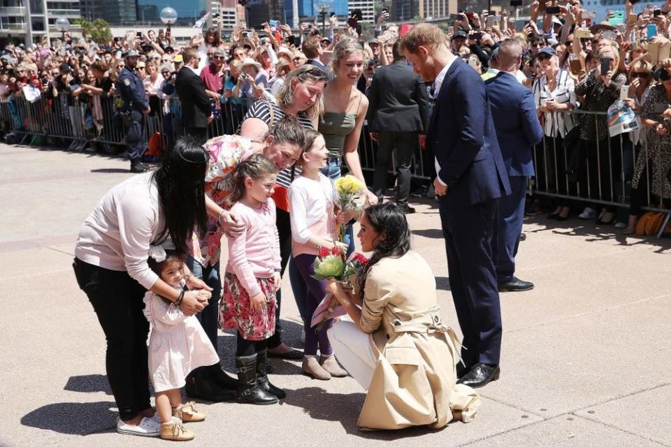Prince Harry and Meghan Markle greeting a bunch of little girls