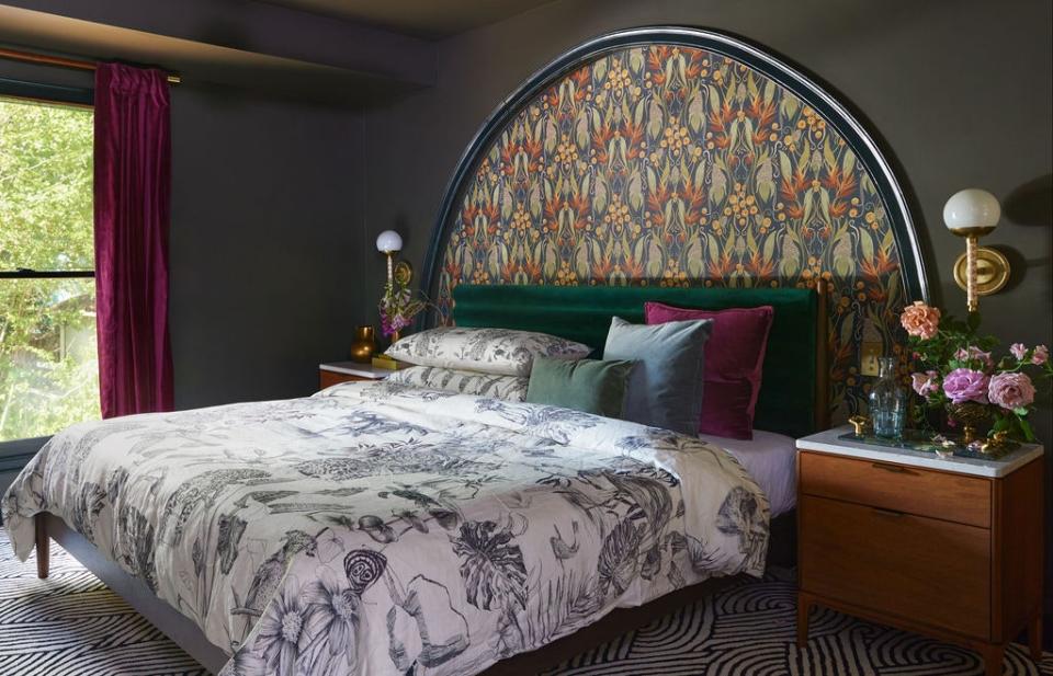 A boutique hotel—that’s how the owner imagined the primary bedroom. In David’s eyes, there was no better way to achieve this than by leaning dark. He created a half-moon alcove behind the bed and emblazoned it with Ruth’s Garden wallpaper from his collection with Chasing Paper. “It’s named after my other grandmother. She loved flowers and would always give people a bunch when they visited her,” he reminisces. He outfitted the alcove with hidden switches and USB ports, “so once she’s in bed, she doesn’t have to get out.” The West Elm nightstands echo the brooding vibe. The gilded lights and area rug are both Anthropologie designs.