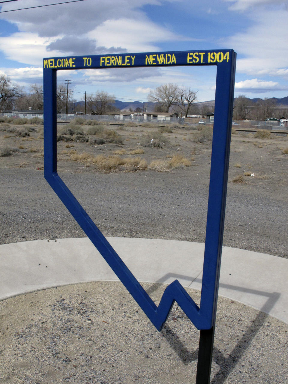 This Thursday, March 18, 2021 photo in Fernley, Nev. shows a sign at a park marking the founding of the town about 30 miles east of Reno in 1905. The founders were lured to the West with the promise of free land and cheap water. Now, the city is suing the U.S. government over plans to renovate an earthen irrigation canal that burst and flooded nearly 600 homes in in 2008. (AP Photo/Scott Sonner)