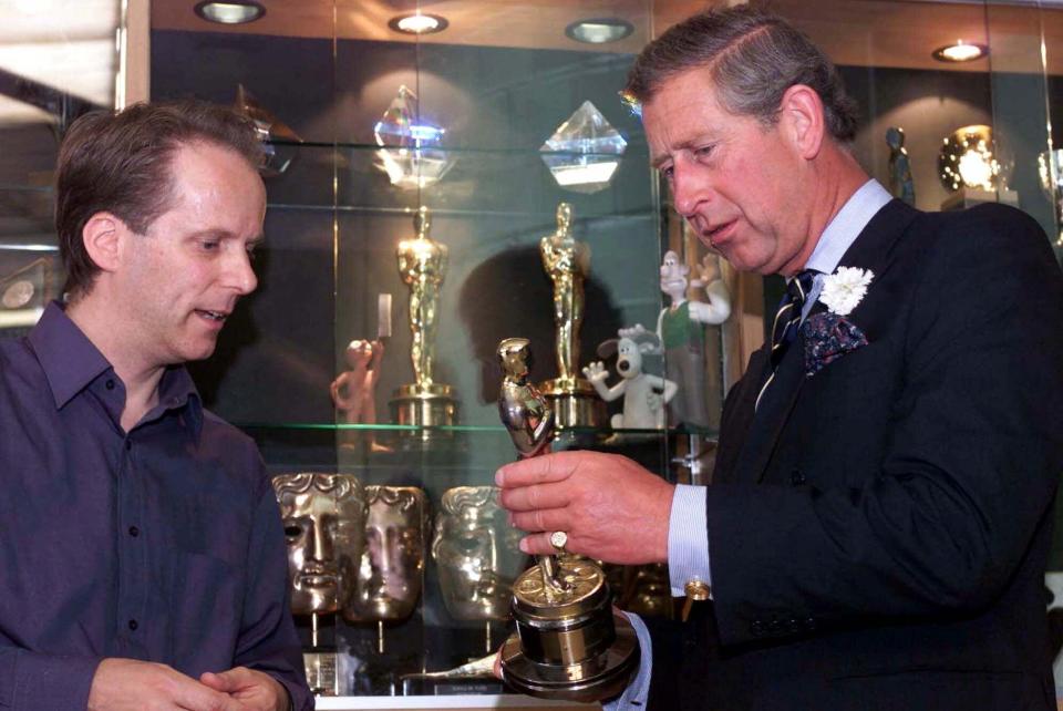 Prince Charles, right, examines an Oscar won by makers of the films starring animated characters Wallace and Gromit with company director Nick Park, in Bristol, England, Monday, July 2, 2001. The Prince laughed and joked with model makers and animators as Park showed him a number of models from the three Wallace and Gromit films and sets from the studio's cinema hit from last year, Chicken Run. (AP Photo/ Paul Grover, Pool)