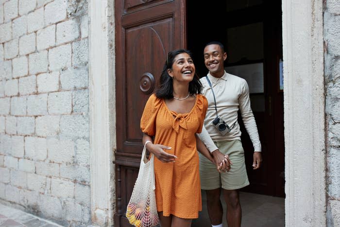 Two people smiling and walking out of a building, appearing happy and connected