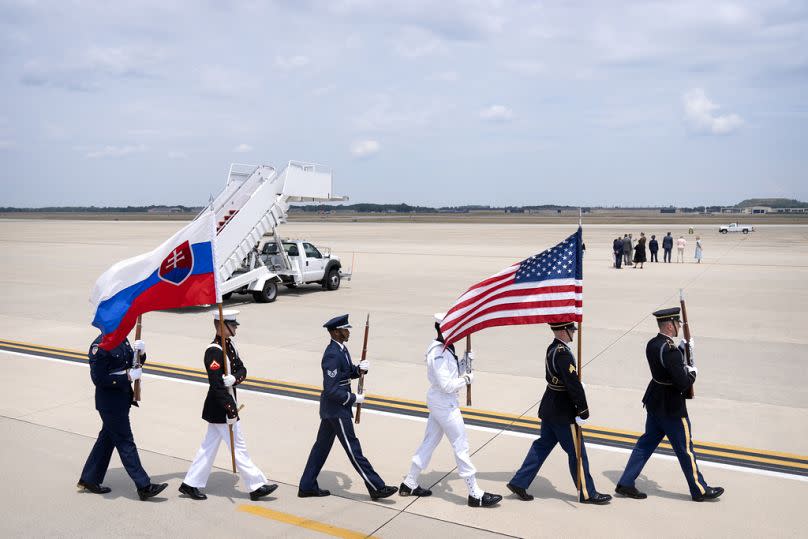 An honor guard carries US and Slovakian flags as they march across the tarmac before the arrival of Slovakia's President Peter Pellegrini, 8 July 2024