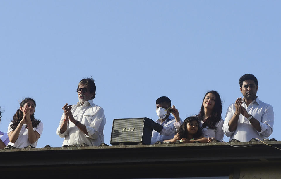 Bollywood actors Amitabh Bachchan (2L) and his son Abhishek Bachchan (R) with wife Aishwarya Rai Bachchan (2R) along with their daughter Aaradhya (3R) clap from atop a residential building to thank essential service providers during a one-day Janata (civil) curfew imposed amid concerns over the spread of the COVID-19 novel coronavirus, in Mumbai on March 22, 2020. (Photo by Sujit Jaiswal / AFP) (Photo by SUJIT JAISWAL/AFP via Getty Images) / Credit: SUJIT JAISWAL