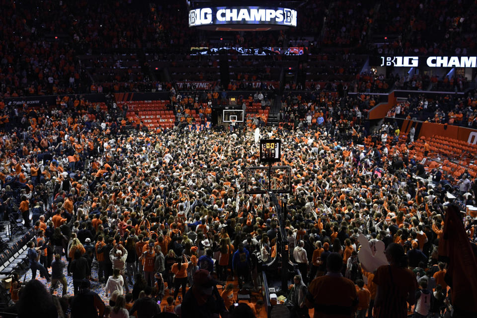 FILE - Illinois fans storm the court at the conclusion of an NCAA college basketball game against Iowa, Sunday, March 6, 2022, in Champaign, Ill. Recent incidents in college basketball have underscored the potential dangers that come from jubilant fans storming the court after the game comes to an end. Finding a solution is proving to be a challenge. (AP Photo/Michael Allio, File)