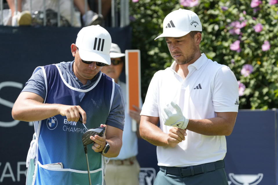 Xander Schauffele watches his caddie Austin Kaiser tighten his driver head on the first hole during the final round of the BMW Championship golf tournament, Sunday, Aug. 20, 2023, in Olympia Fields, Ill. (AP Photo/Charles Rex Arbogast)