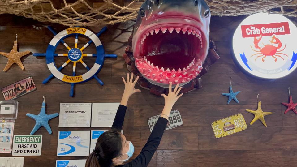 The Crab General’s Angel Chen has fun with shark jaws, one of many entertaining marine and nautical displays within the new restaurant.