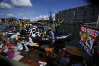 Police, rear, prevented protetesting farmers from taking part in the Pride Canal Parade as thousands of people lined canals in the Dutch capital to watch the colorful spectacle of the 25th edition after the last two events were canceled due to the COVID-19 pandemic, in Amsterdam, Netherlands, Saturday, Aug. 6, 2022. The banner at right reads "No Farmer No Food". (AP Photo/Peter Dejong)