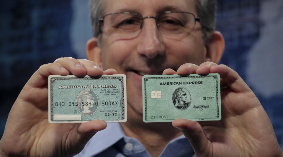 In this Wednesday, Oct. 23, 2019, photo Ira Galtman, American Express director of corporate archives, shows the original American Express "Green Card," left, with its latest version in New York. For 50 years the "Green Card" was everywhere and has been revamped, with a new look and more travel benefits. (AP Photo/Bebeto Matthews)