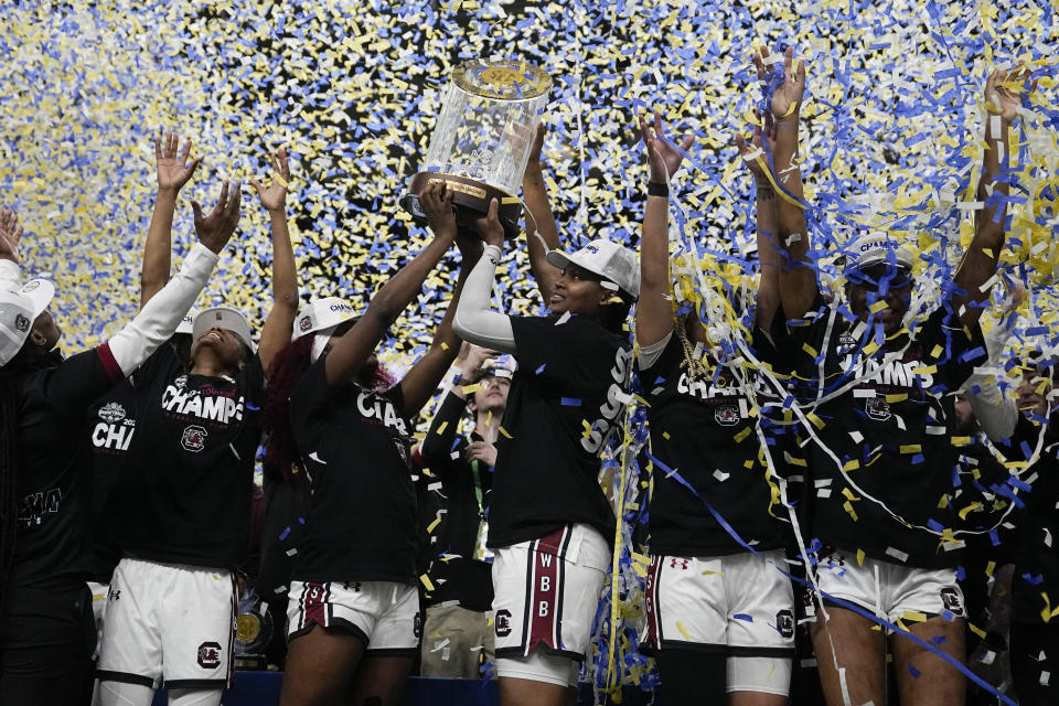 South Carolina celebrates with the trophy and teammates after their win against LSU in an NCAA college basketball game at the Southeastern Conference women's tournament final Sunday, March 10, 2024, in Greenville, S.C. (AP Photo/Chris Carlson)