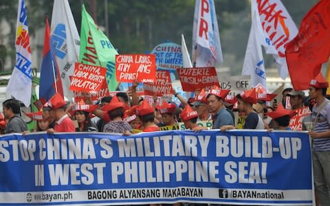 Activists carry placards during a protest in front of the Chinese consulate in Manila on February 10, 2018, against Beijing's claims in the South China Sea  - Credit: AFP