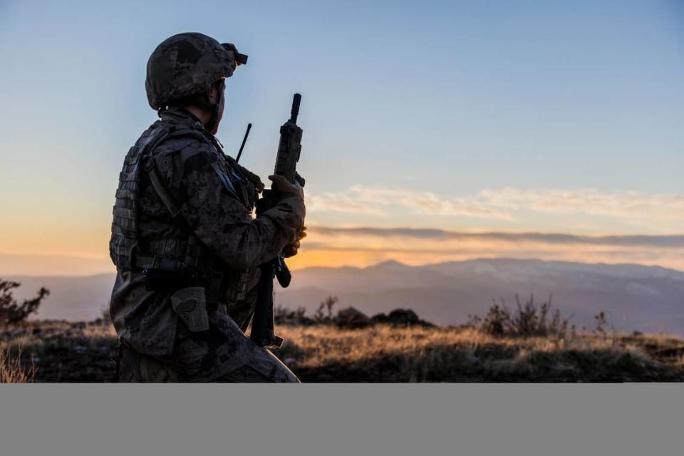 Mujer del ejército de EEUU en guardia viendo el atardecer en un campo de batalla. 