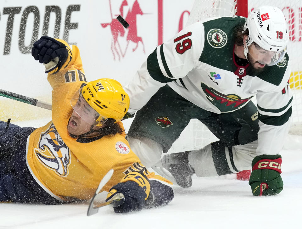 Nashville Predators left wing Kiefer Sherwood (44) and Minnesota Wild center Nic Petan (19) battle for the puck during the second period of an NHL hockey game Thursday, April 13, 2023, in Nashville, Tenn. (AP Photo/Mark Humphrey)