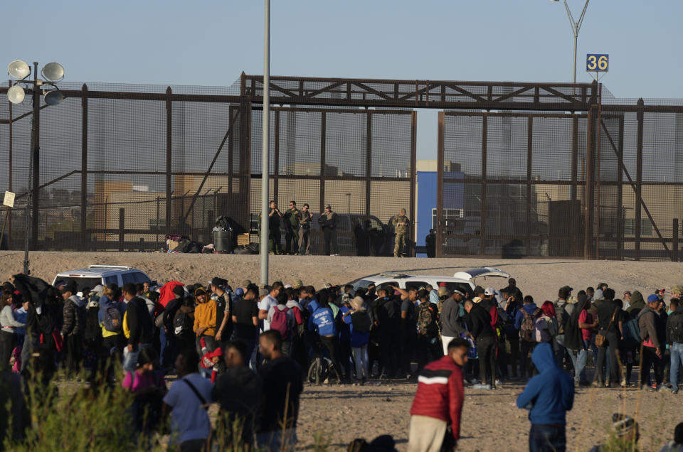 Migrants mill around on the U.S. side of the border next to a gate guarded by U.S. authorities, after crossing from the Mexican side in Ciudad Juarez, Wednesday, March 29, 2023, a day after dozens of migrants died in a fire at a migrant detention center in Ciudad Juarez. (AP Photo/Fernando Llano)