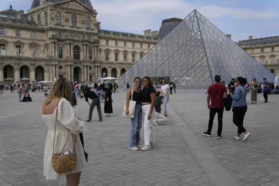 Tourists take pictures in front of the Pyramide in the Louvre Museum courtyard, in Paris, France, Monday, June 20, 2022. Tourism is on the rebound around the world this summer after two years of pandemic restrictions, with museums and flights packed – but the global recovery is hampered by inflation and rising virus infection rates in many regions. (AP Photo/Francois Mori)