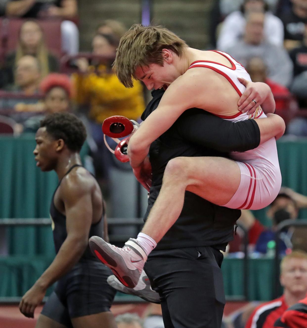 Wadsworth's Chris Earnest, right, leaps into the arms of wrestling coach Clay Wenger after beating Perrysburg's Wynton Denkins, left, by major decision to win the D150 pound Division I state title during the OHSAA State Wrestling Tournament at the Jerome Schottenstein Center on Sunday.