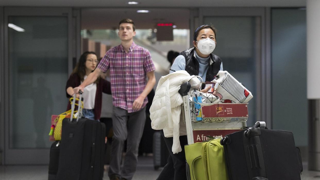 Eine Frau trägt am Toronto Pearson International Airport eine Atemschutz-Maske. Immer mehr Länder prüfen eine Evakuierung ihrer Landsleute.