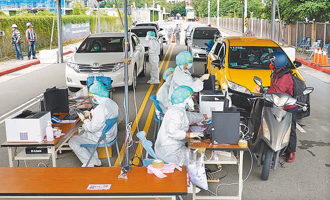 北投士林科技園區設置車來速篩檢站，民眾5日駕車或騎車接受採檢，醫護人員著全套防護裝為民服務。（姚志平攝）