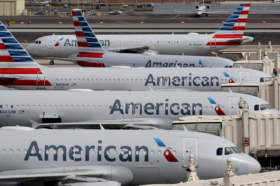 FILE - In this Wednesday, March 25, 2020 file photo, American Airlines jets sit idly at their gates as a jet arrives at Sky Harbor International Airport in Phoenix. The Trump administration is raising the possibility of the U.S. government getting ownership stakes in U.S. airlines in exchange for $25 billion in direct grants to help the carriers survive a downturn caused by the coronavirus pandemic, according to people familiar with the matter, Thursday, March 26, 2020. (AP Photo/Matt York, File)