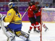 Switzerland's Jessica Lutz (R) celebrates her goal against Sweden's goalie Valentina Wallner (L) with teammate Switzerland's Sara Benz (13) during the third period of their women's ice hockey bronze medal game at the Sochi 2014 Winter Olympic Games February 20, 2014.