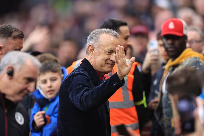 Tom Hanks waves to fans as he attends Aston Villa vs Liverpool