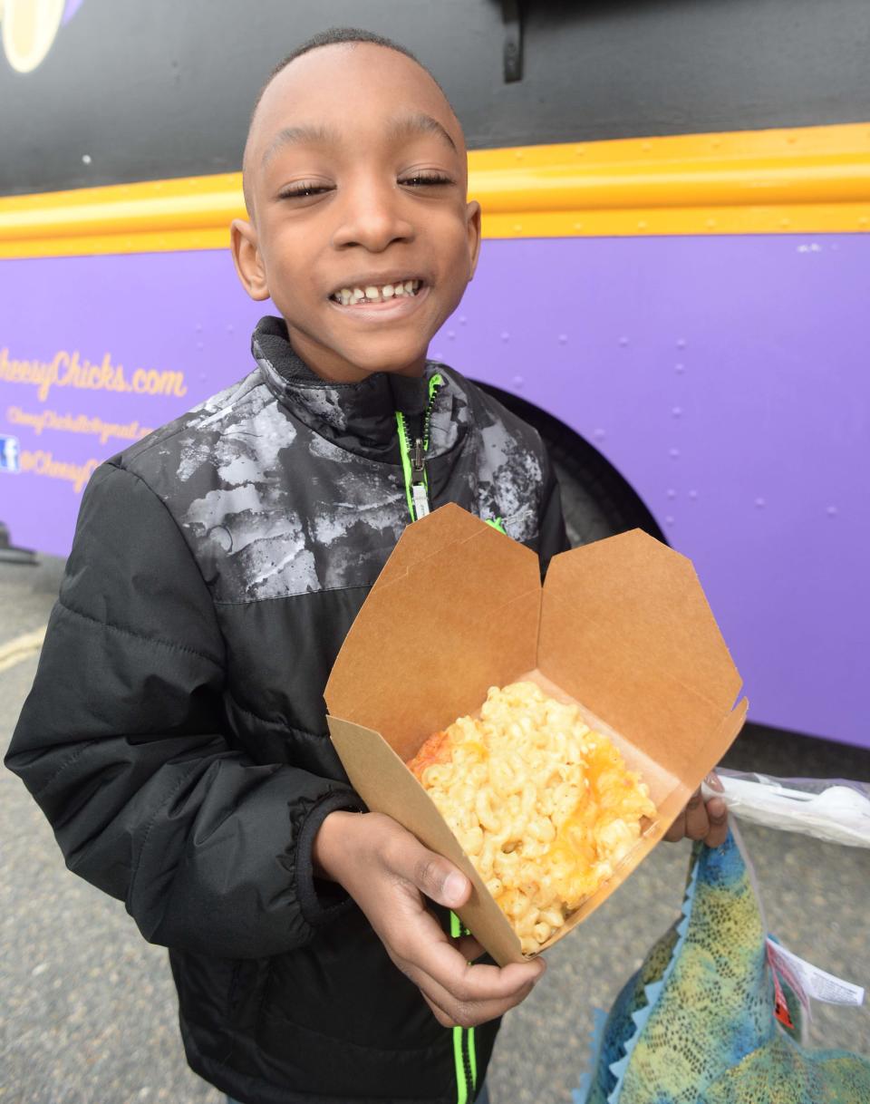 Nolan Garcov, 7, shows off his mac and cheese from the Cheesy Chicks food truck outside Abington Town Hall on Saturday, May 7, 2022.