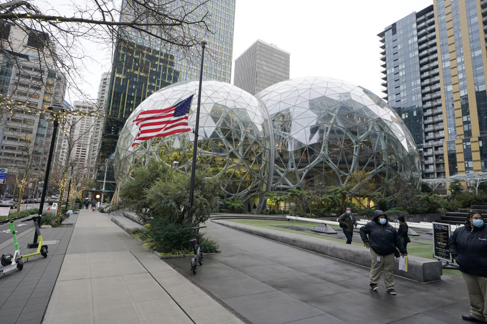 A U.S. flag flies in front of the Amazon Spheres on the company's corporate campus in downtown Seattle, Tuesday, Dec. 7, 2021. Amazon Web Services suffered a major outage Tuesday, the company said, disrupting access to many popular sites. The company provides cloud computing services to many governments, universities and companies, including The Associated Press. (AP Photo/Ted S. Warren)