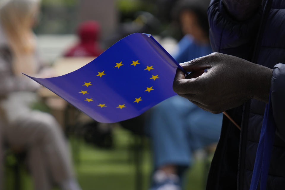 FILE- A man holds a European Union flag as he walks outside the European Commission building during Europe Day celebrations in Brussels on May 4, 2024. The European Union marks Europe Day on Thursday, May 9, but instead of the traditionally muted celebrations, all eyes are on the EU elections in one month time which portend a steep rise of the extreme right and a possible move away from its global trendsetting climate policies. (AP Photo/Virginia Mayo File)