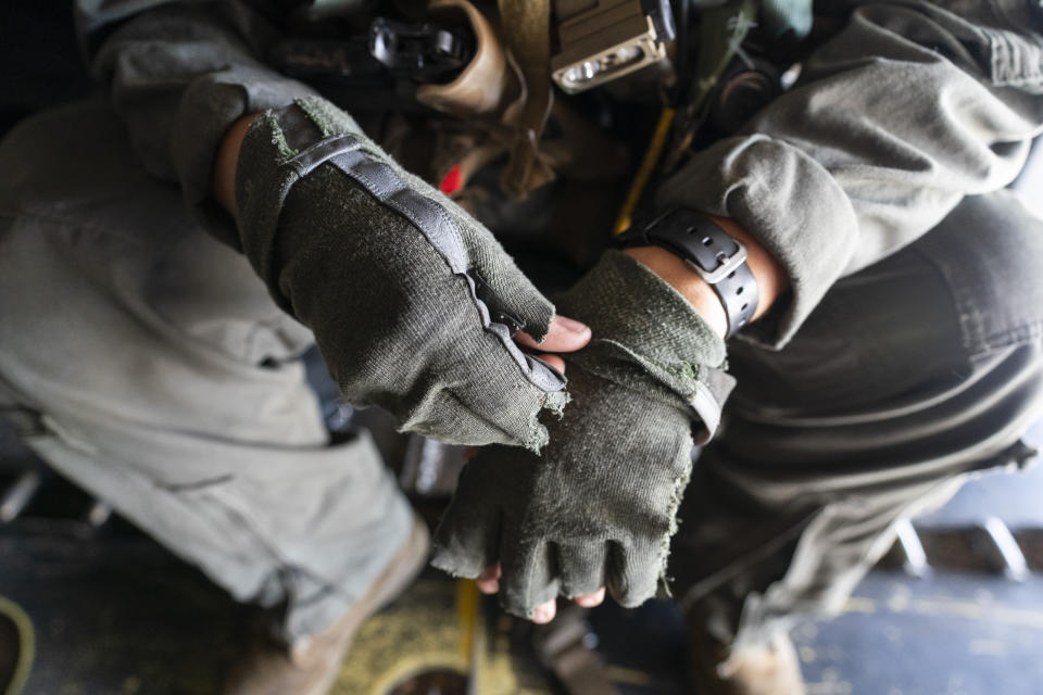 U.S. Marine Cpl. Thalles Souza, a crew chief on a VM-22 Osprey, with VMM-266, "Fighting Griffins," from Marine Corps Air Station New River, from Jacksonville, N.C., adjusts his gloves en route to Toussaint Louverture International Airport, Saturday, Aug. 28, 2021, in Port-au-Prince, Haiti. A 7.2 magnitude earthquake on Aug. 22, caused heavy damage to the country. (AP Photo/Alex Brandon)