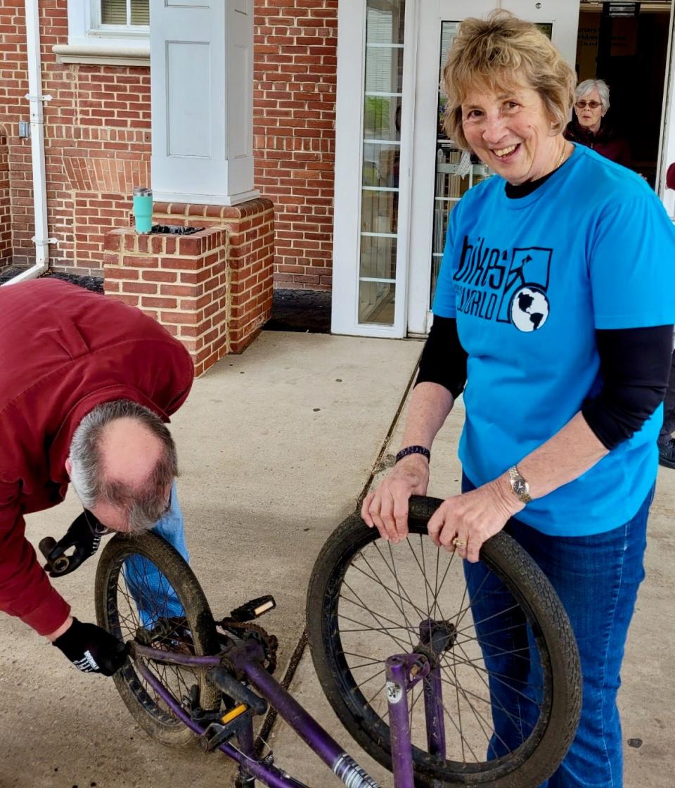 Cindy Brown, co-coordinator of Otterbein United Methodist Church's bike collection effort for Bikes for the World, at the church's annual bike collection event in 2023. With Brown is Gregg McFarland, who is prepping one of the bikes.